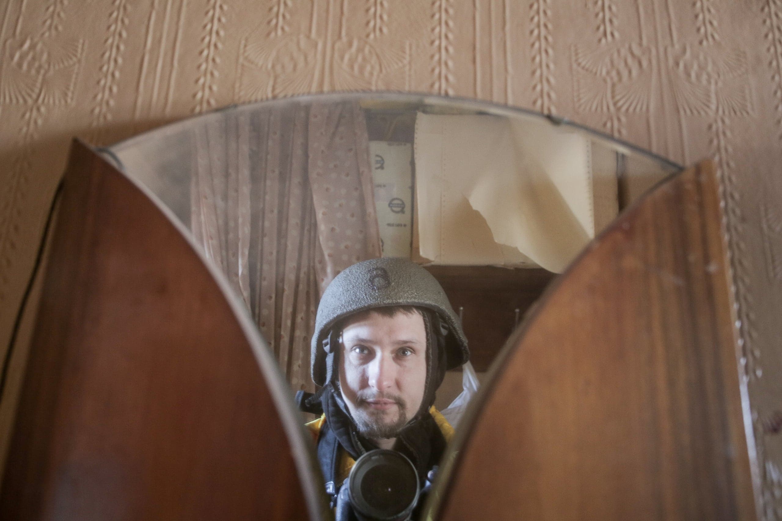 Мужчина в шлеме с камерой (селфи) отражается в изогнутом зеркале.