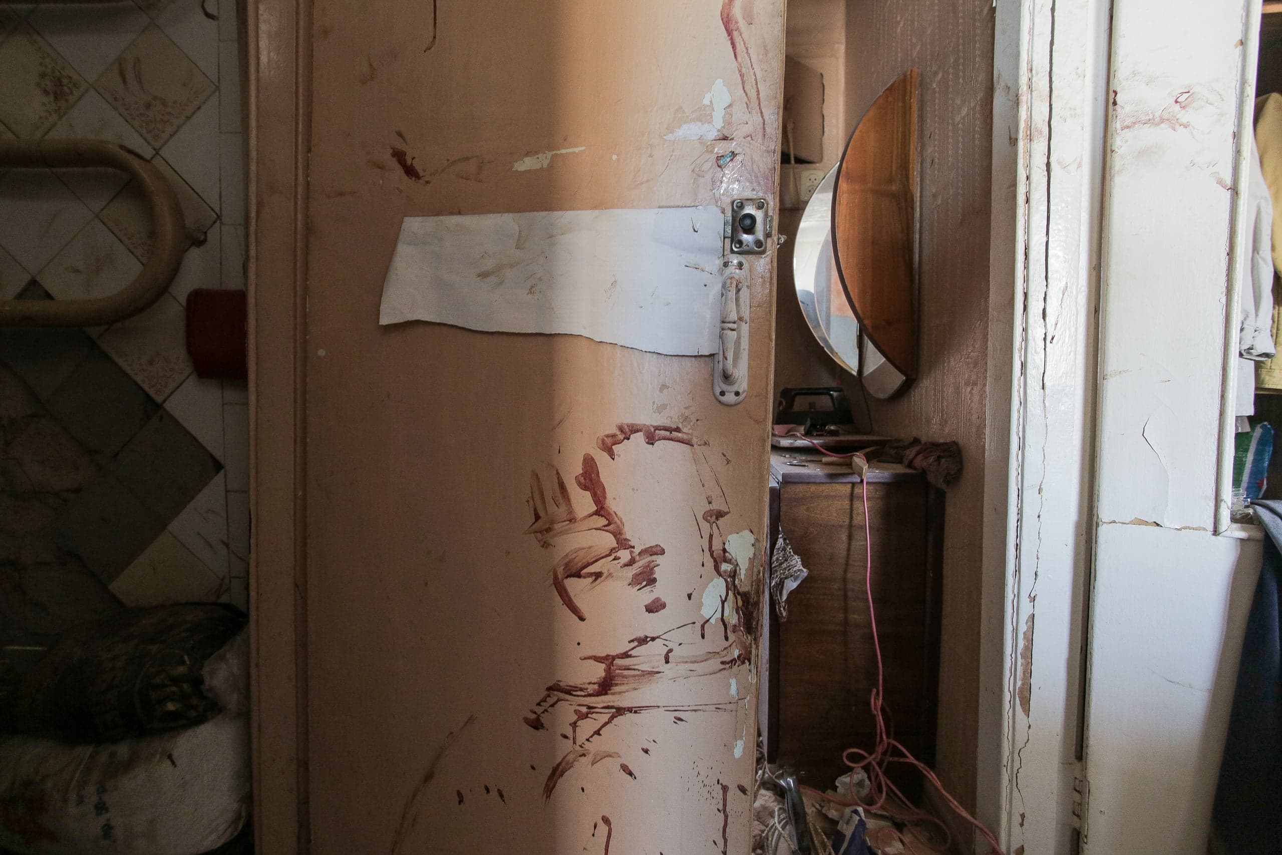 Приоткрытая испачканная старая дверь между комнатами