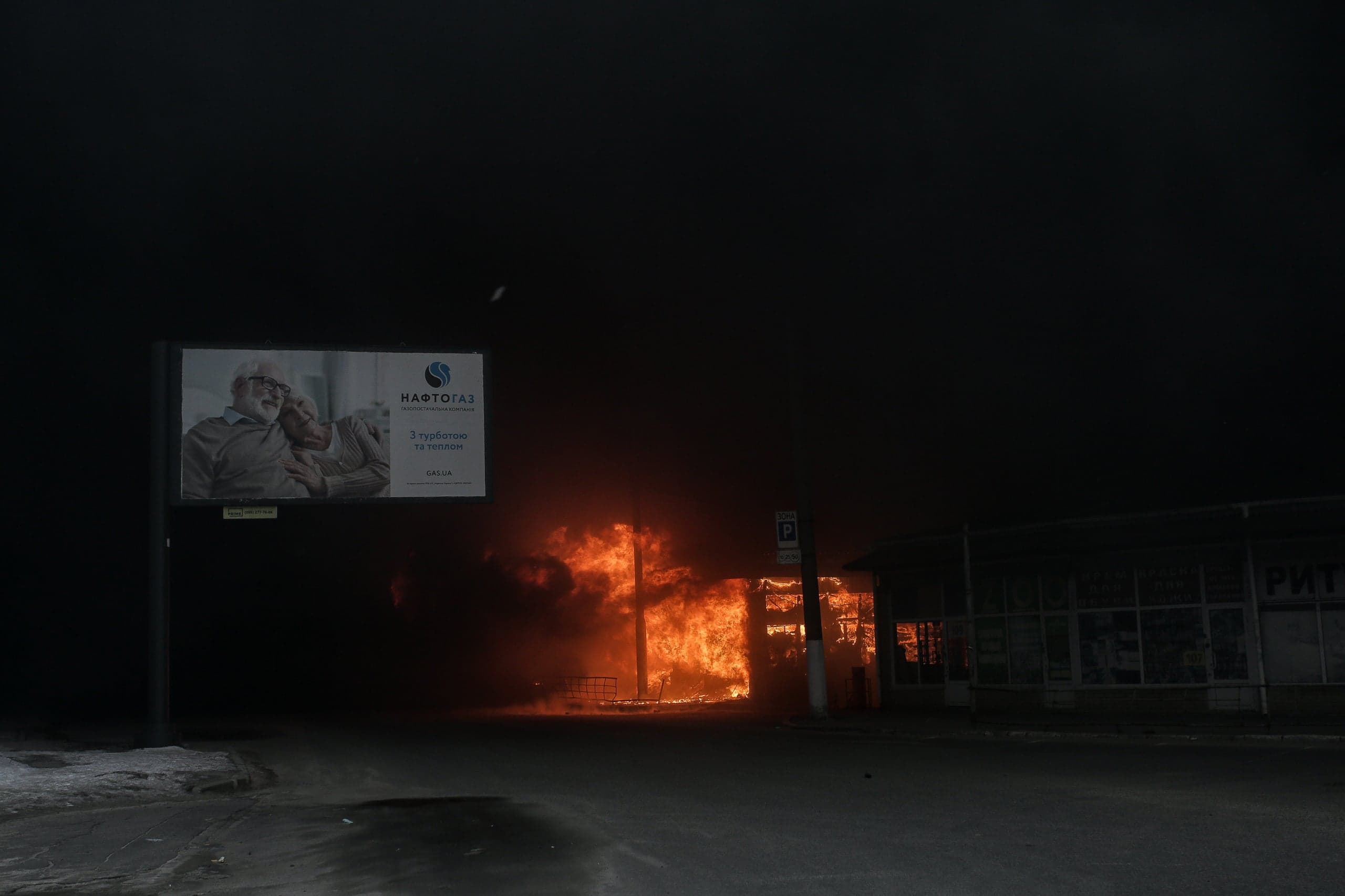 Ночь. Горящее здание на улице рядом с рекламным щитом "НАФТОГАЗ: З турботою та теплом".