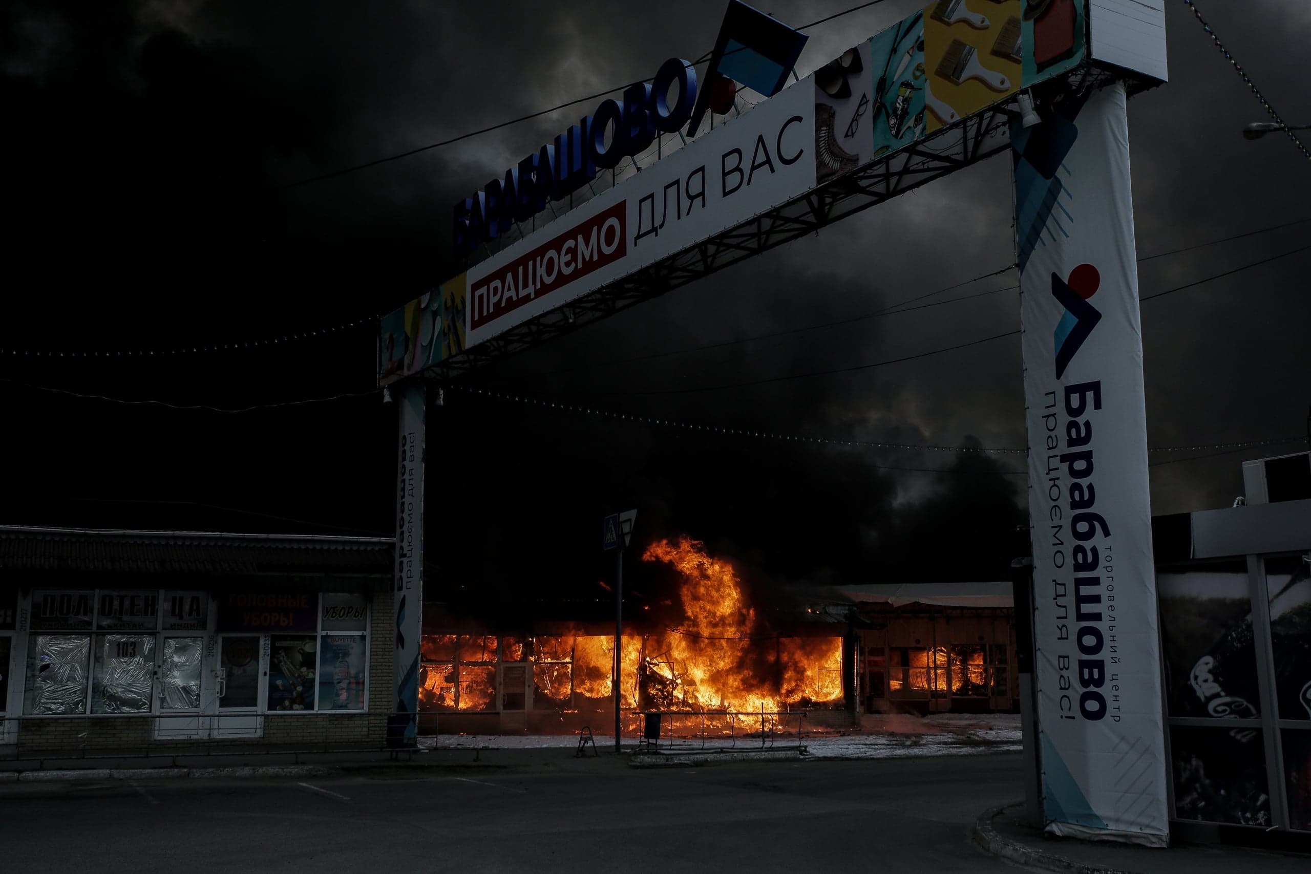 Сильный пожар и густой черный дым в здании, расположенном под рекламной аркой с надписями "БАРАБАШОВО" и "ПРАЦЮЄМО ДЛЯ ВАС".