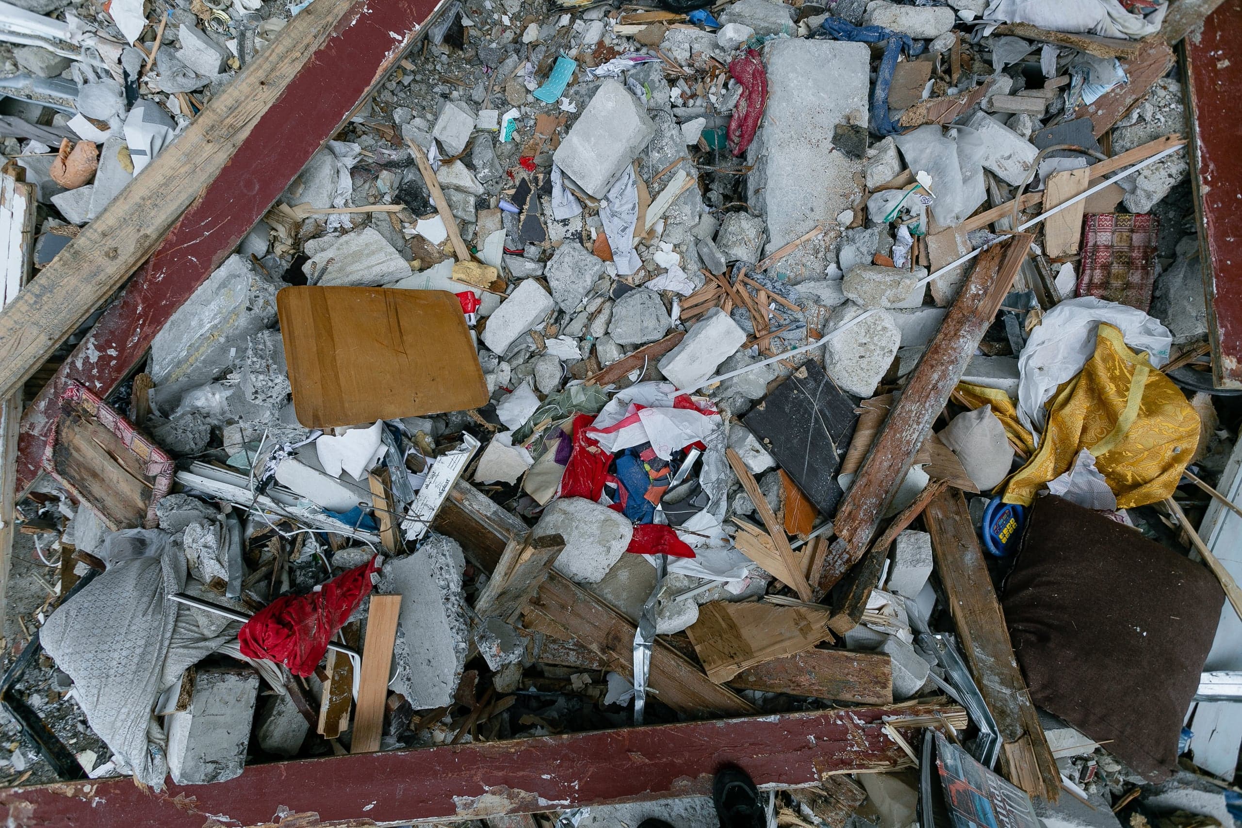 Груда строительного мусора, бетонного щебня, деревянных обломков и порванной ткани.