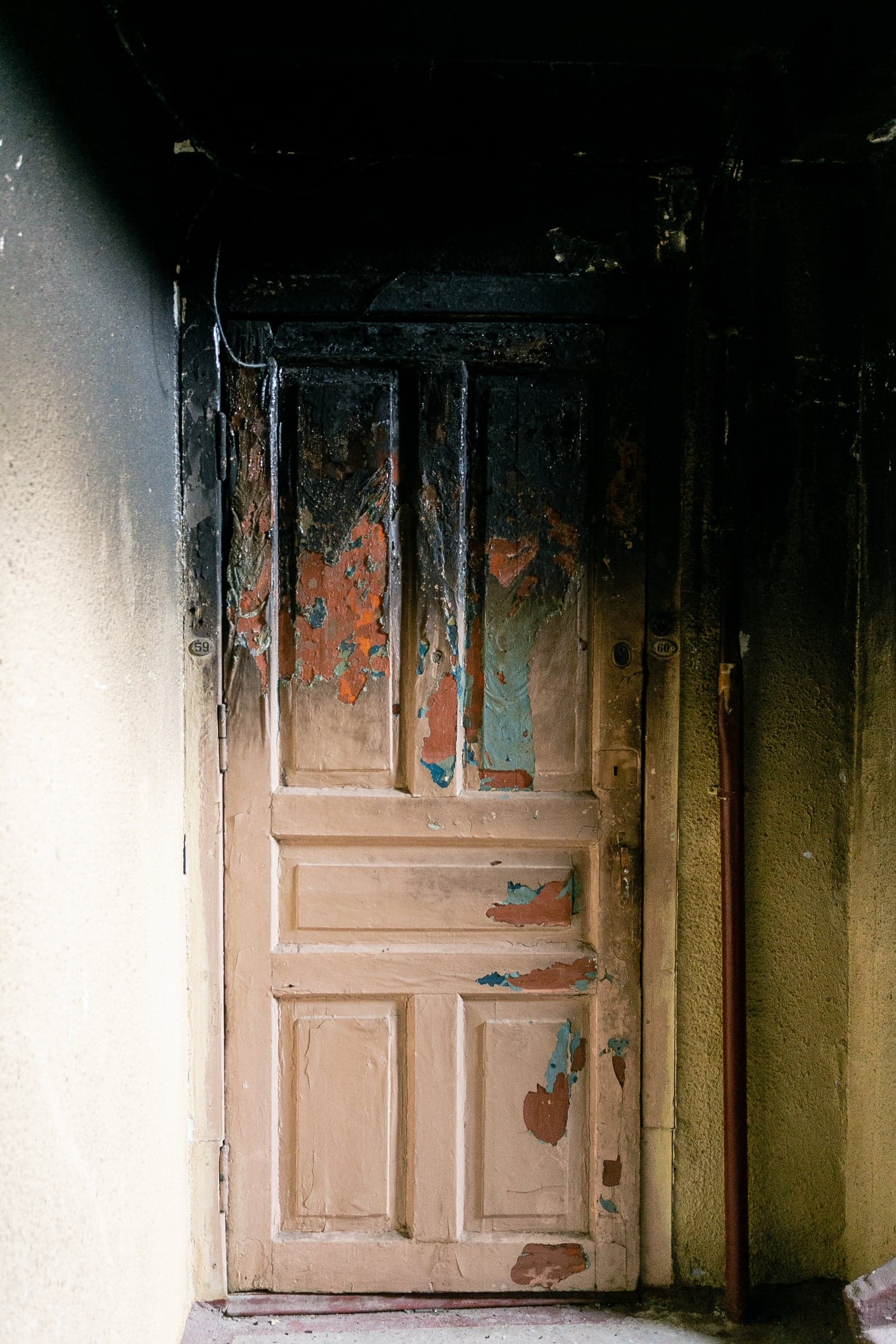 Обугленная дверь с облупившейся краской; на косяке номер "69".