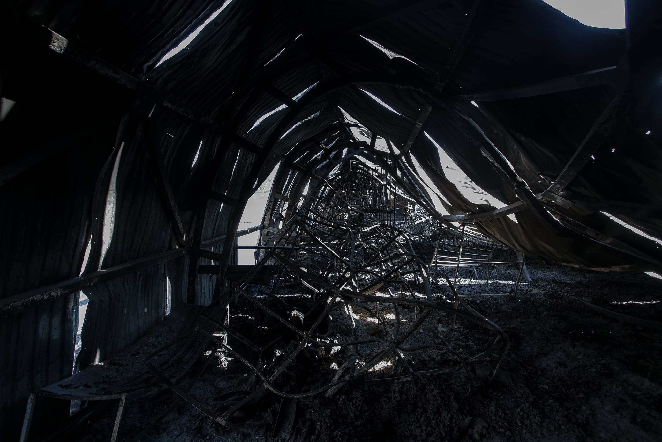Обугленный интерьер разрушенного арочного сооружения с просветами света.
