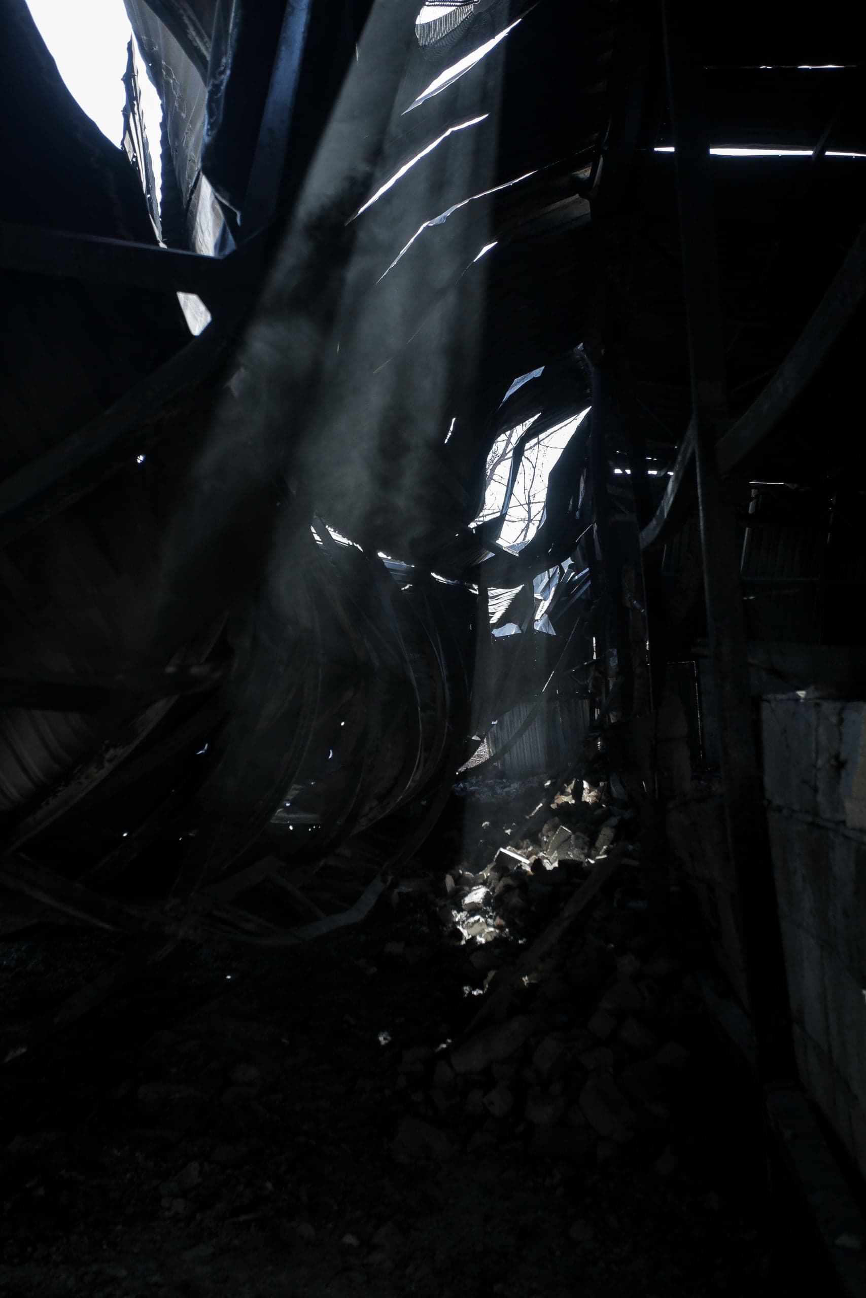 Темное разрушенное помещение. Лучи света проникают сквозь проломы в потолке, освещая пыль и кучу обломков.