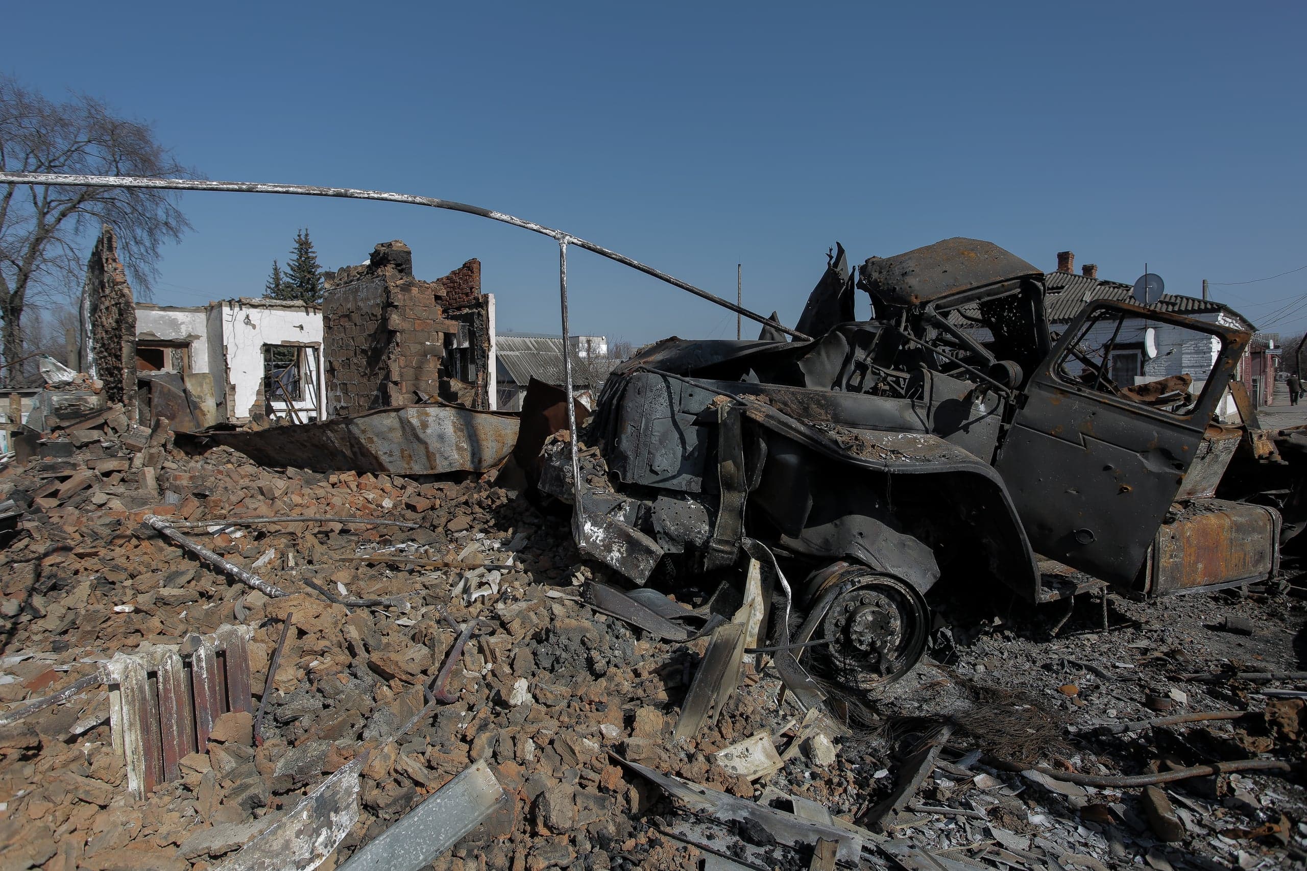 Сгоревший остов автомобиля среди руин и обломков разрушенных зданий.