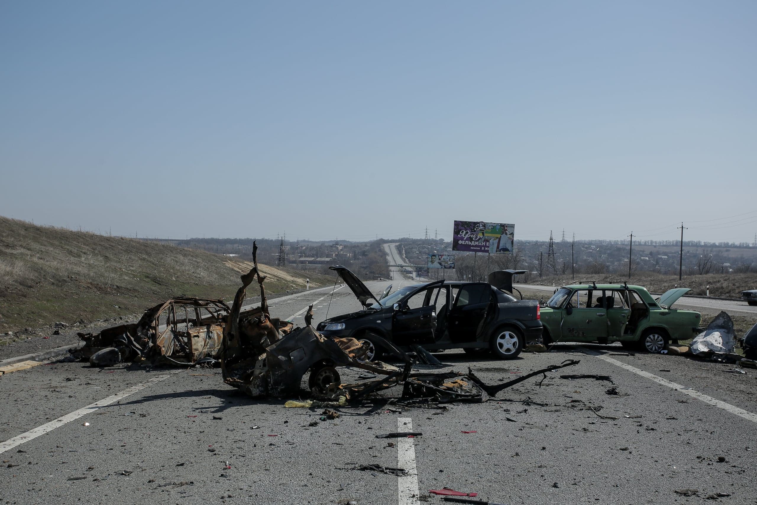 Сгоревшие и поврежденные гражданские автомобили, блокирующие шоссе.