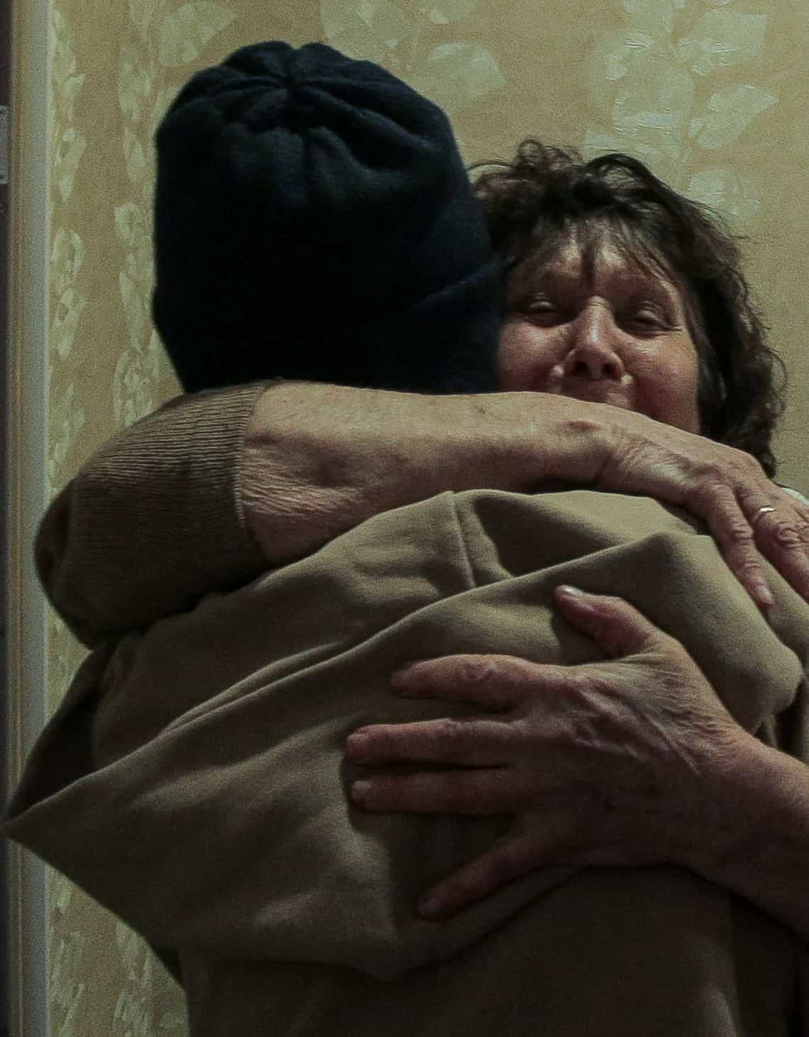 Эмоциональное объятие двух человек, одна женщина плачет.