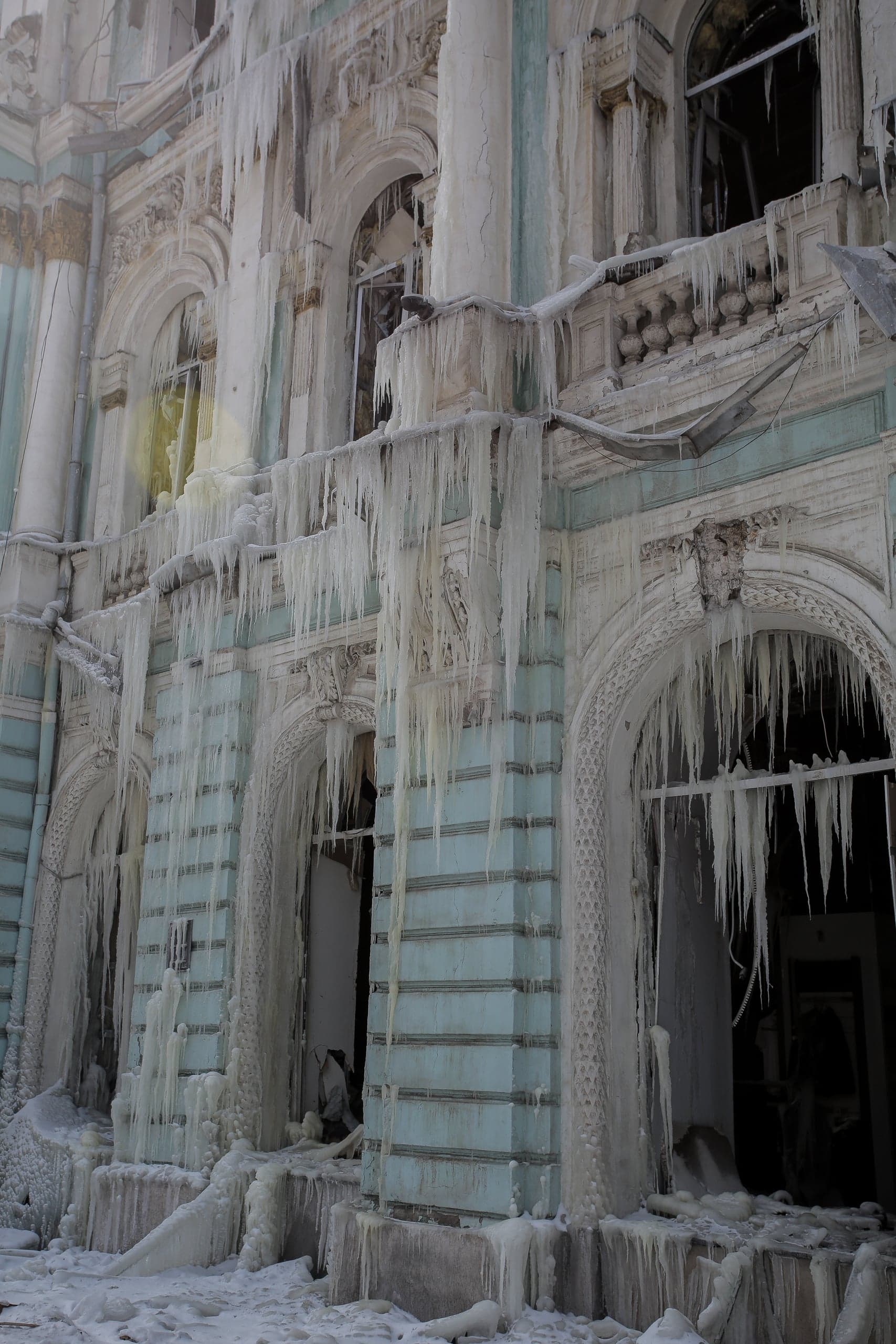 Стена здания с колоннами, повсюду видны сосульки