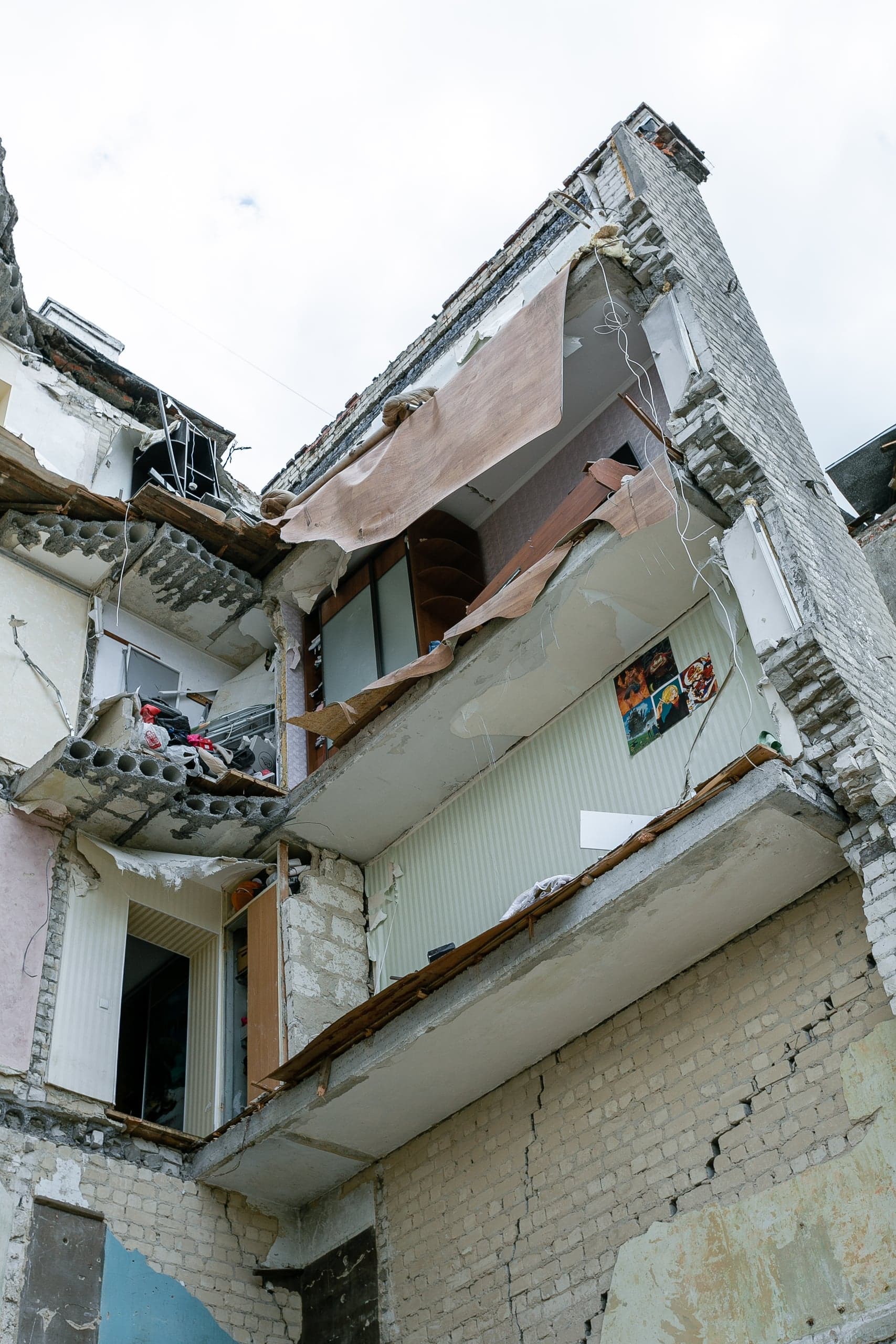 Сильно поврежденный угол многоэтажного жилого дома с обнаженными стенами и интерьерами квартир.