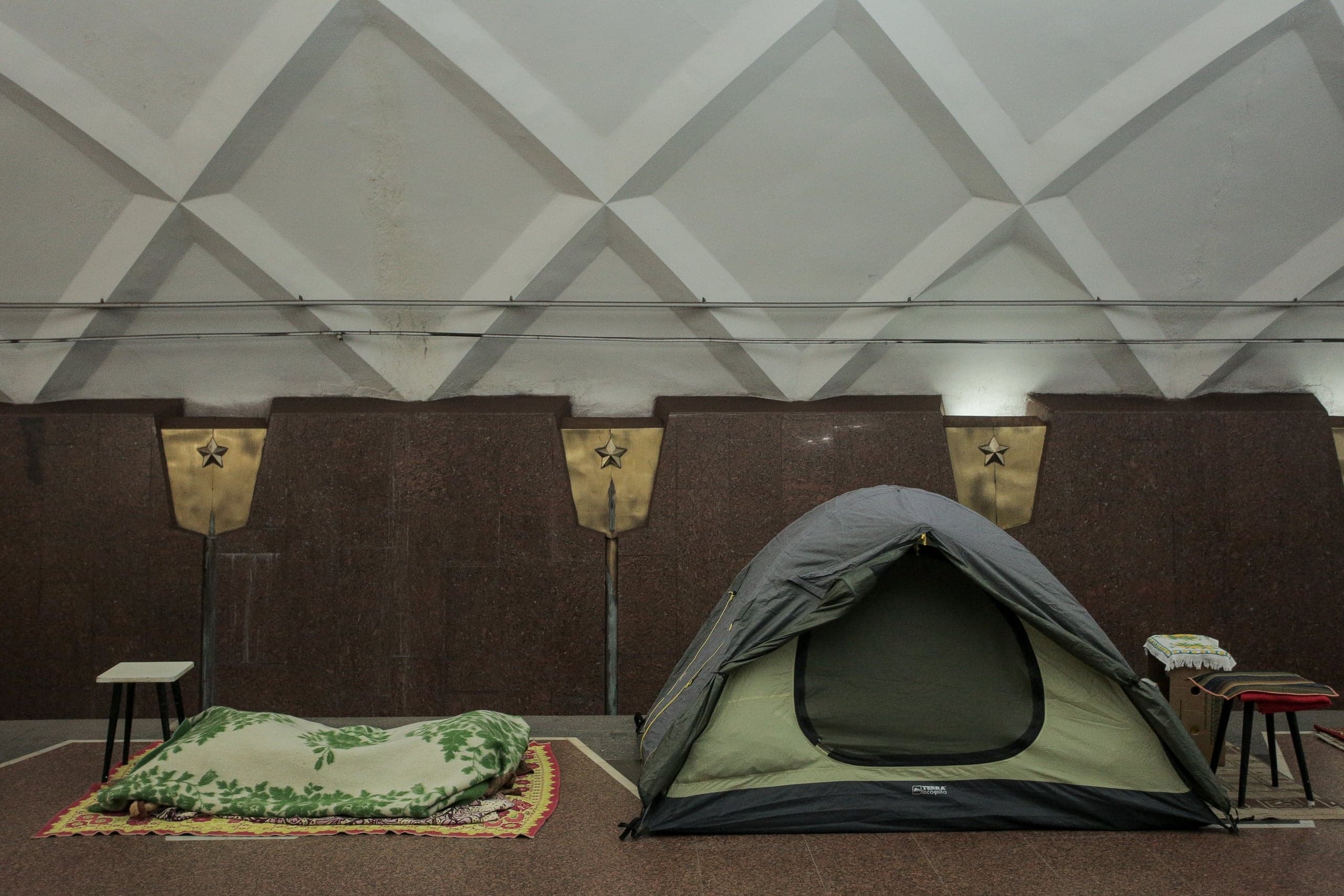 Палатка и спальное место в подземном помещении с монументальным потолком и панелями, украшенными звездами.