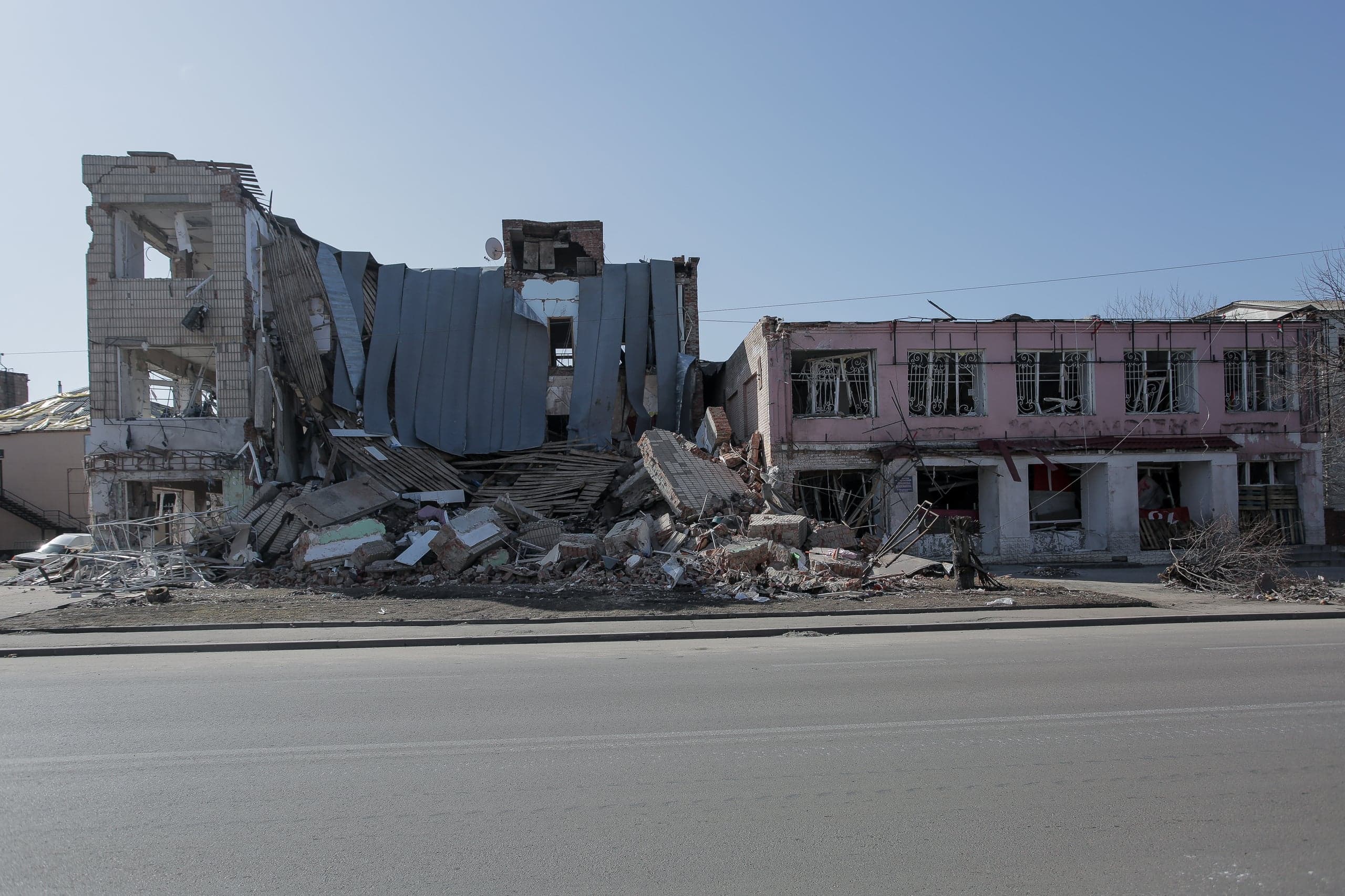 Сильно разрушенные здания и груда обломков на городской улице.