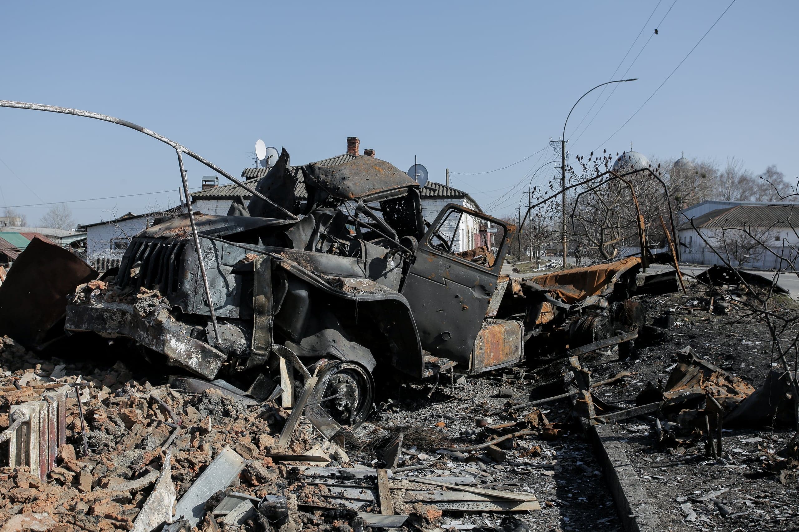 Сильно поврежденный, сгоревший автомобиль на груде руин и обломков.