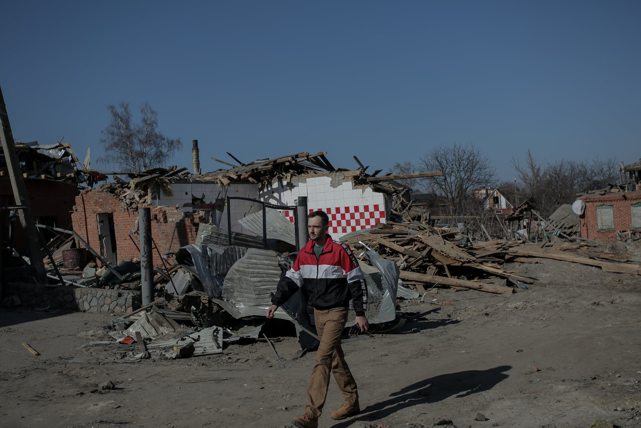 Мужчина идет среди развалин и обломков разрушенных зданий.