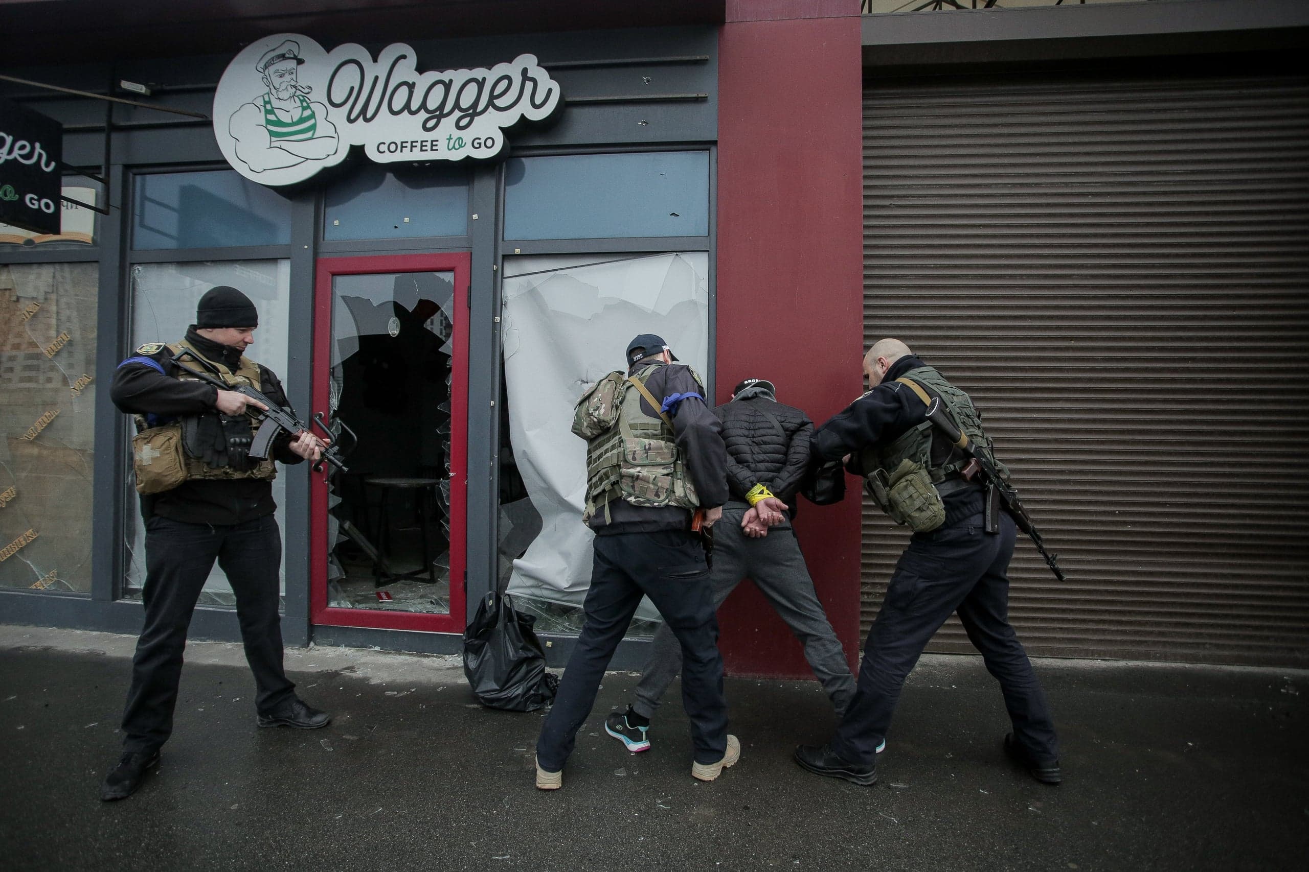 Вооруженные люди задерживают мужчину в наручниках у разбитого входа в кафе "Wagger COFFEE to GO".