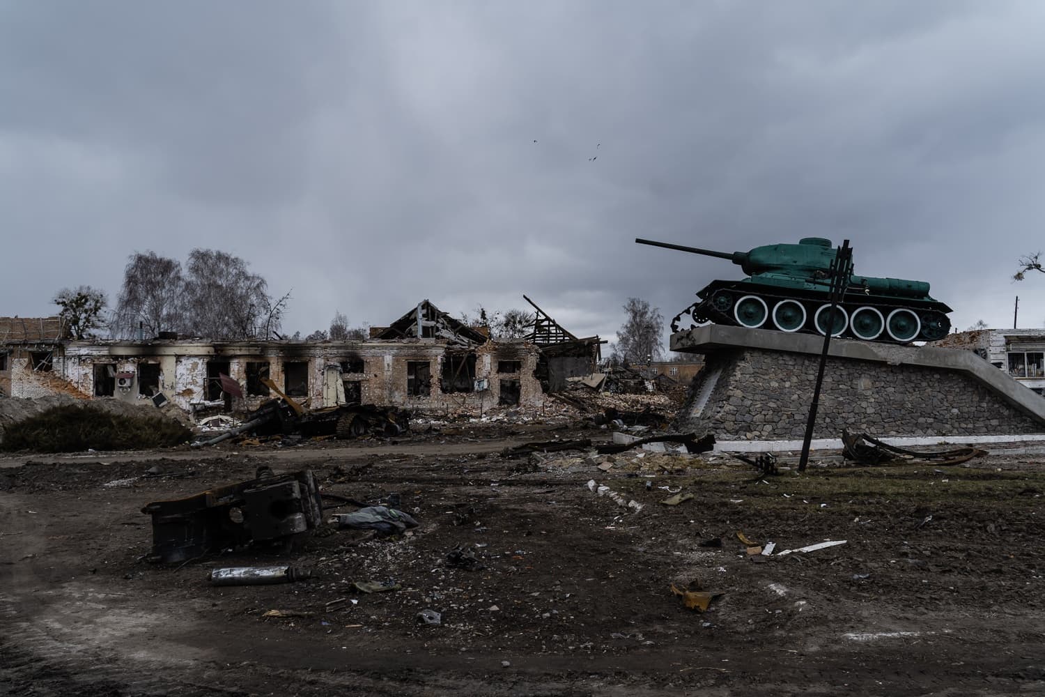 Разрушенное здание и обломки напротив монумента танку Т-34. Пасмурно.