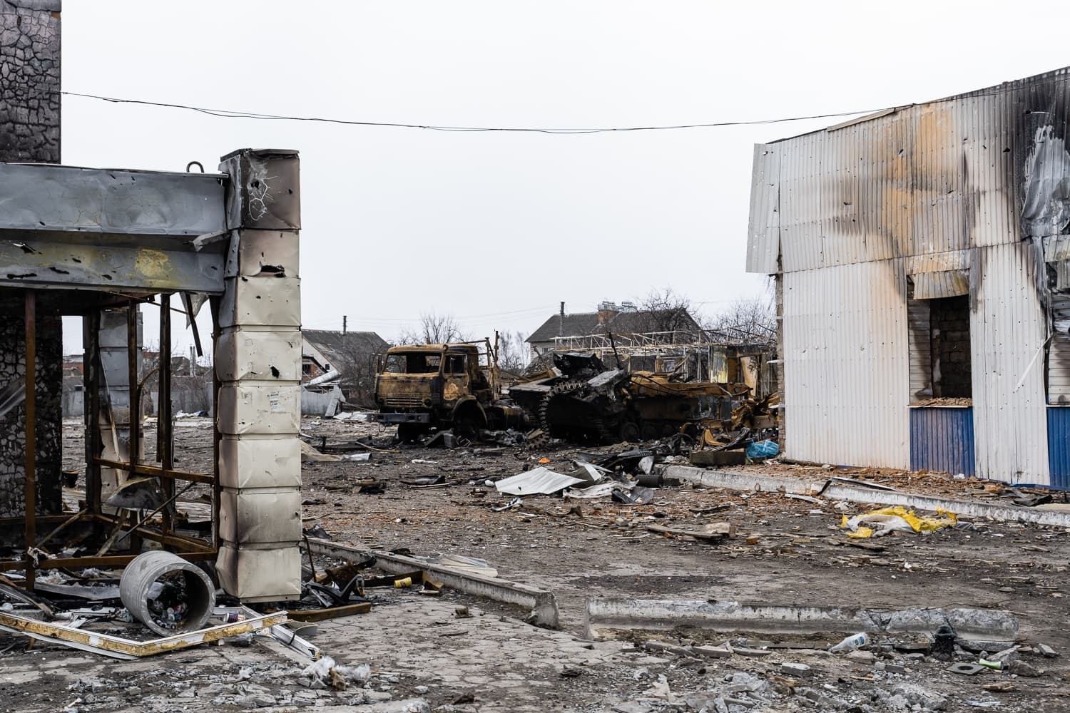 Уничтоженный танк и сгоревший грузовик среди руин зданий.