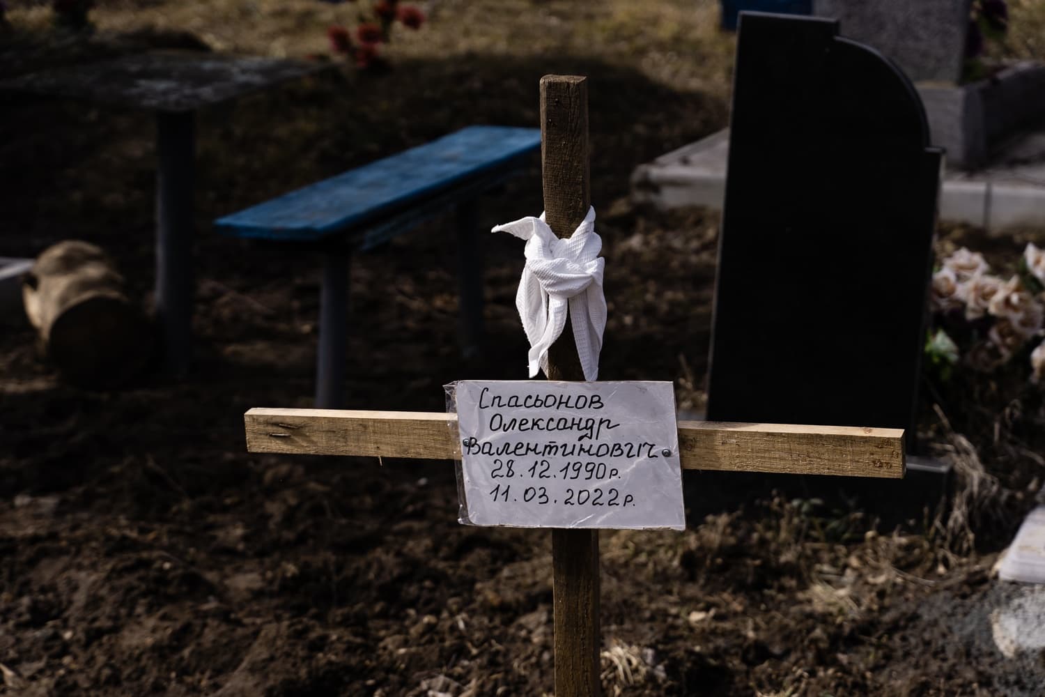 Временный деревянный крест на свежей могиле с надписью: "Спасьонов Олександр Валентинович. 28.12.1990 р. 11.03.2022 р.".