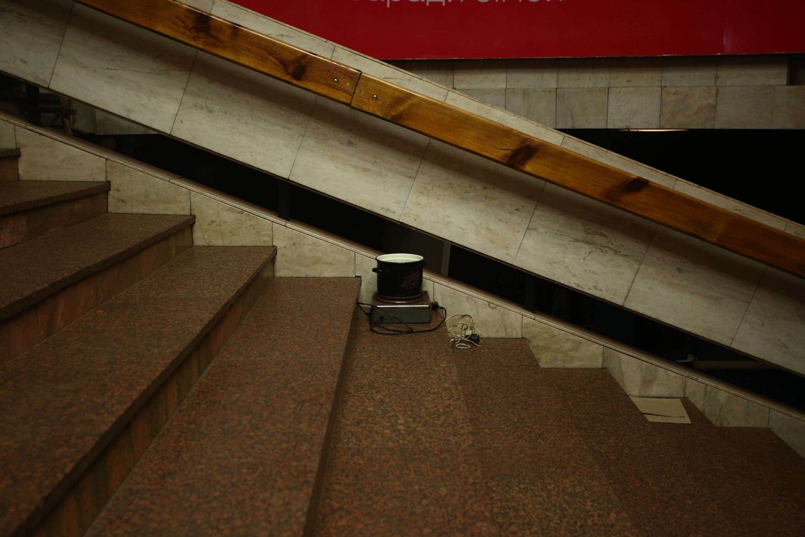 Кастрюля на электрической плитке, установленной на ступеньках гранитного лестничного пролета.