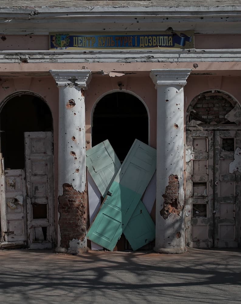 Two loaves of bread and other food items on a wooden log, behind them there is a pile of soil.